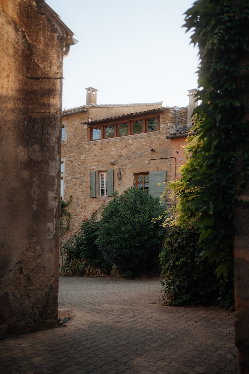 Stone building with green shutters and vines